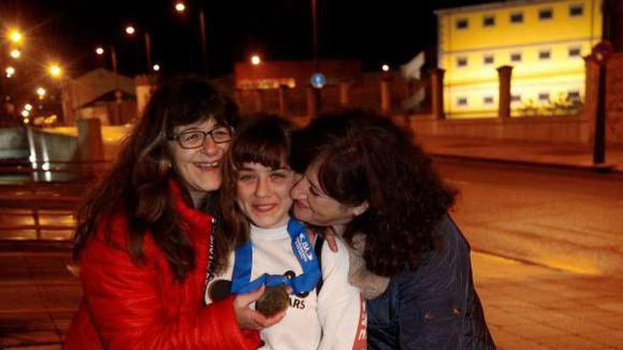 Carmen López, con la medalla al cuello, es felicitada por su madre, Marián (izquierda), y su amiga Rosa, con la perra &quot;Luna&quot; delante.