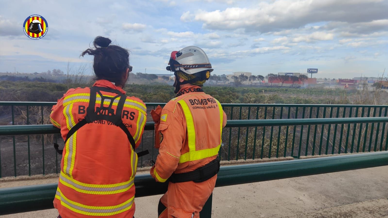 Dos agentes de extinción de incendios observan el área afectada.