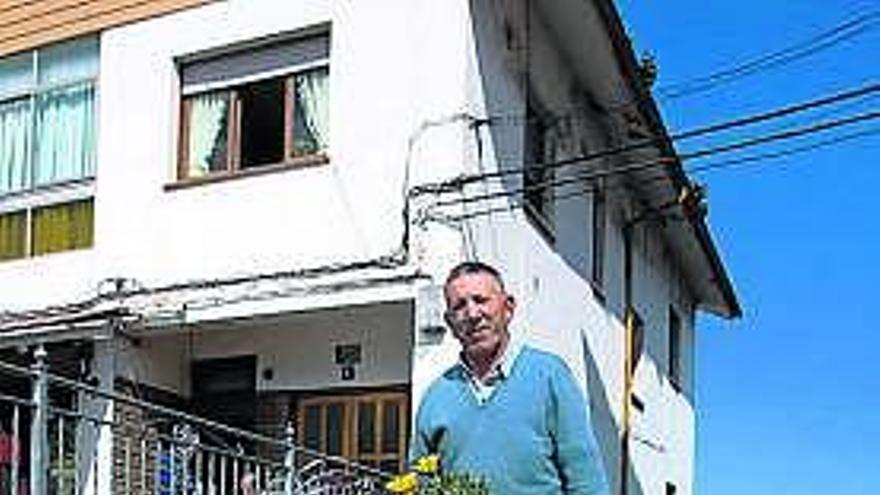 Antonio González espera en la puerta de su peluquería a dos clientes que se acercan por la rampa de acceso.