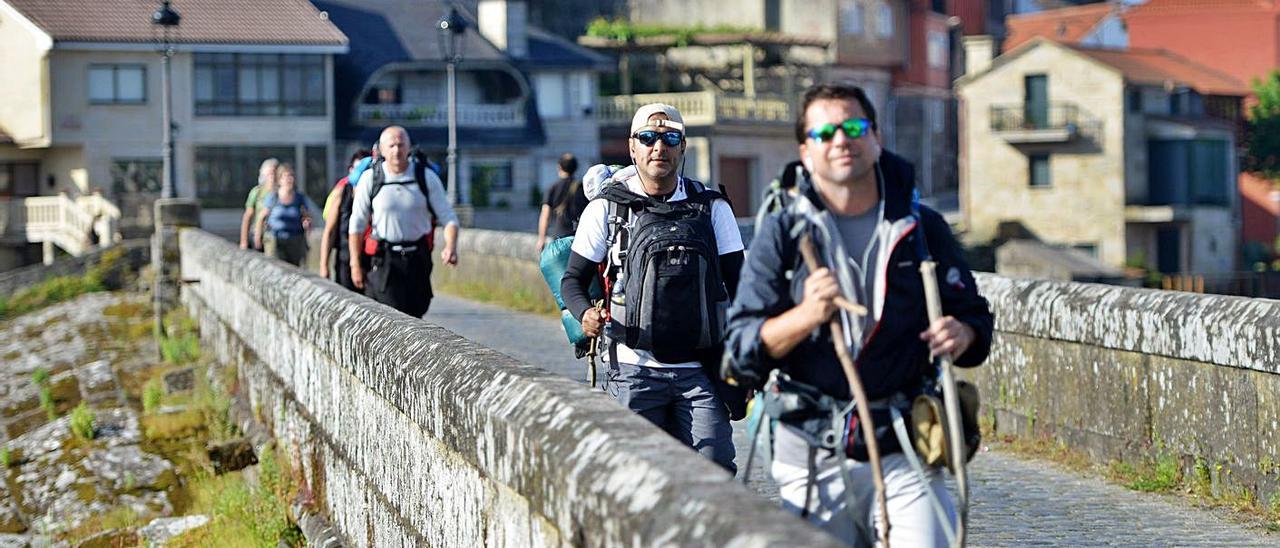 Peregrinos a Santiago, por el puente medieval que conecta Arcade con Pontesampaio. |   // GUSTAVO SANTOS