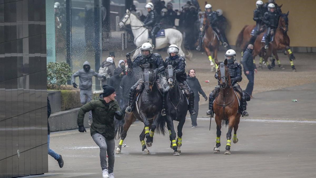 Policía montada a caballo carga contra los manifestantes ultras en Bruselas.