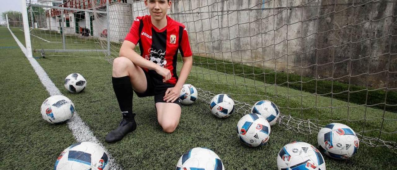 El goleador Adrián Suárez posa con la elástica del Veriña y con varios balones sobre el campo de fútbol de Lloreda.