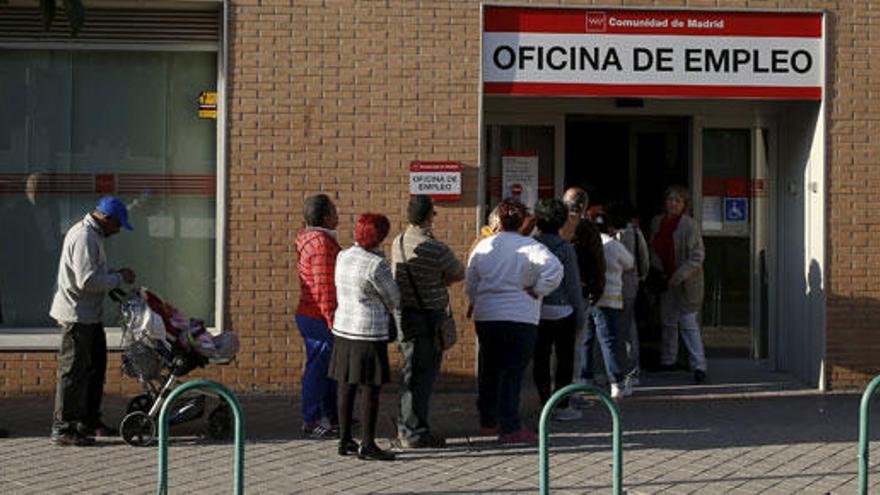 Varias personas hacen cola ante una oficina de empleo.