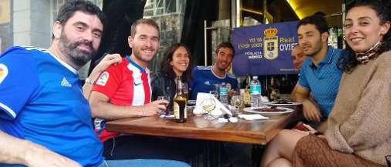 En la imagen superior, dos oviedistas durante el partido. En la inferior, una mesa con aficionados de los dos equipos viendo el partido.