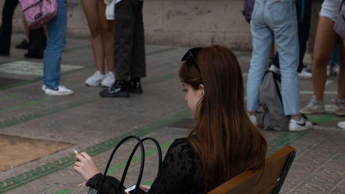 Una mujer fuma en un banco.  | // EUROPA PRESS