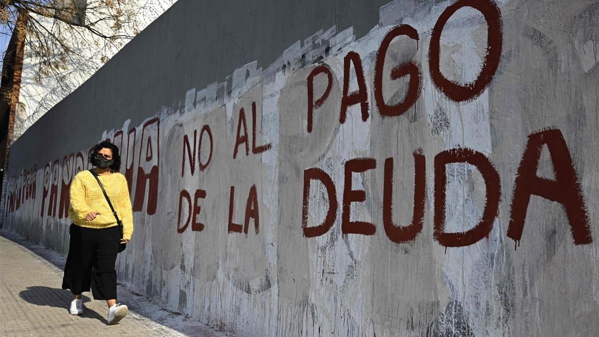 Una mujer camina junto a una pintada que insta a no pagar la deuda, el lunes en Buenos Aires.