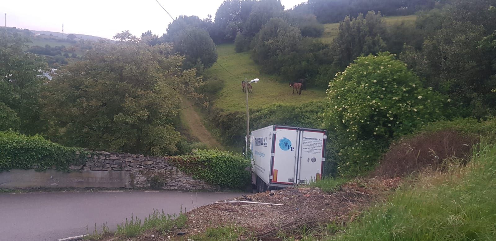 Un camión frigorífico se atasca en un camino rural de Gijón