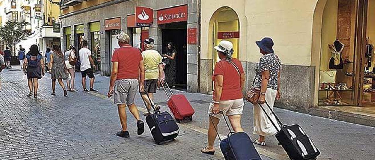 Turistas con sus maletas en la calle Sant Miquel.