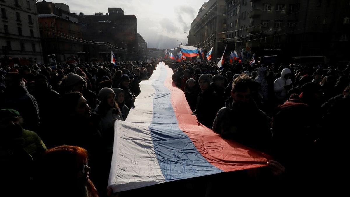 zManifestantes con una bandera rusa durante la manifestación de Moscú para recordar al asesinado Borís Nemtsov.