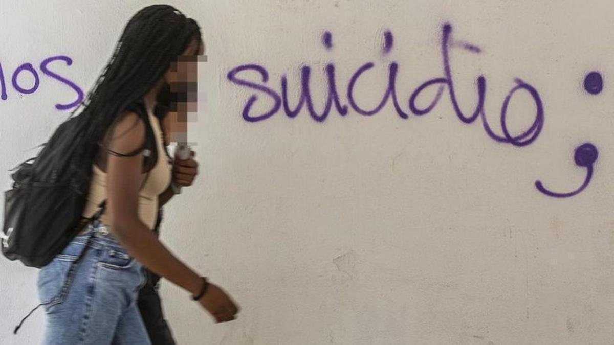 Dos jóvenes, pasan ante una pintada sobre suicidio.