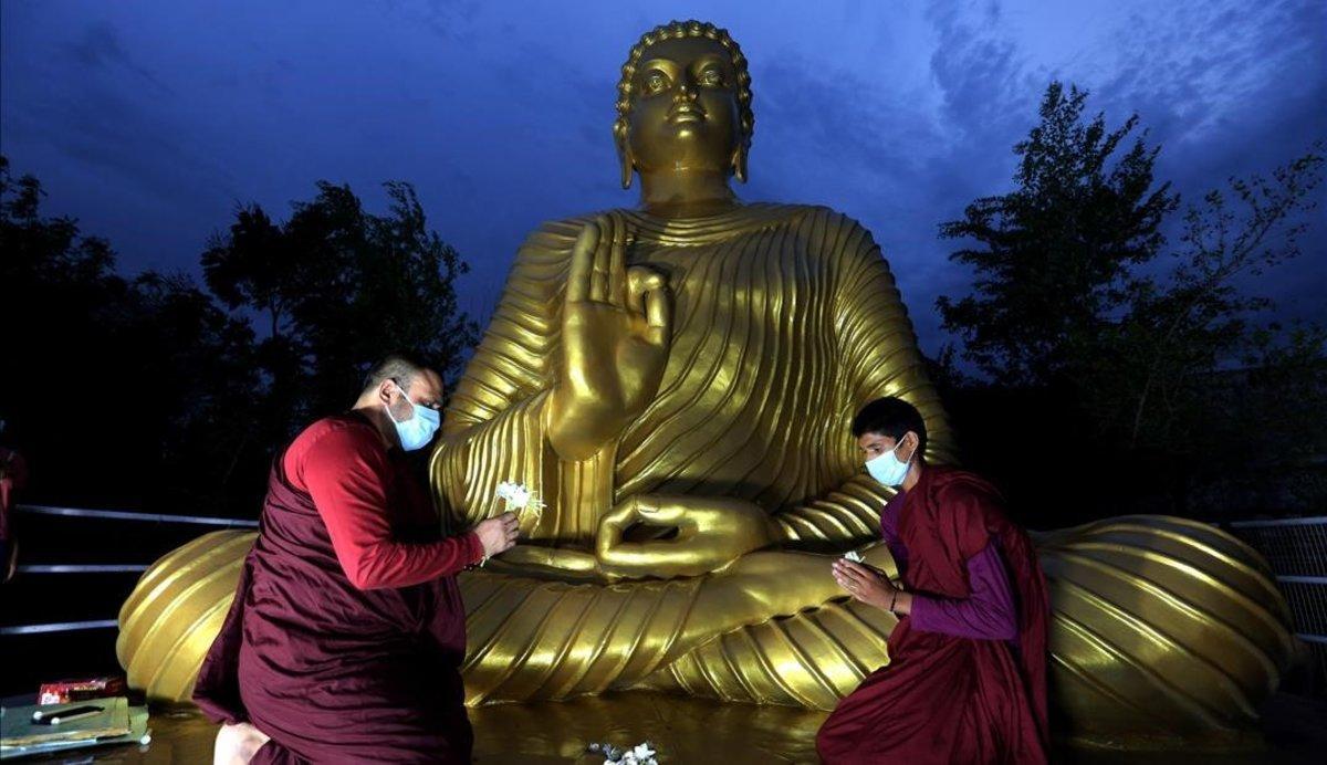  Monjes budistas con mascarilla rezan frente a una estatua de Buda en Bhopal, India.
