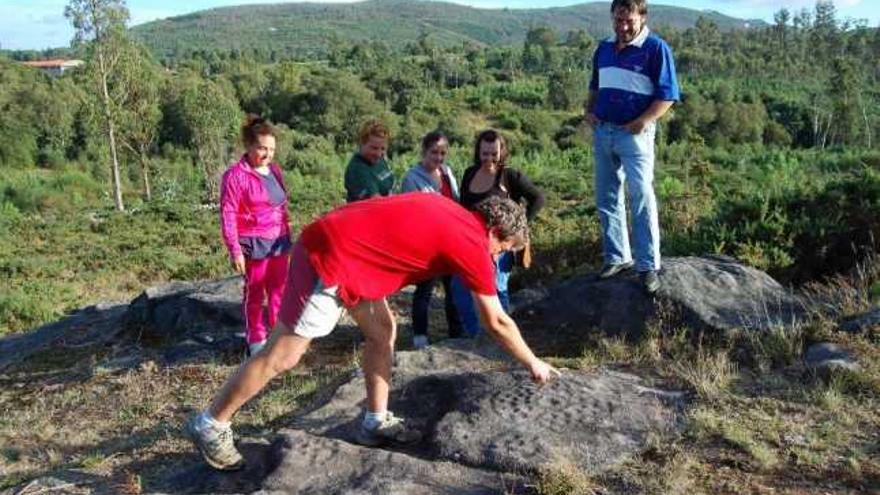 El vicepresidente de los comuneros, Antonio Graña, muestra unos petroglifos en el monte de Amoedo.  // Faro