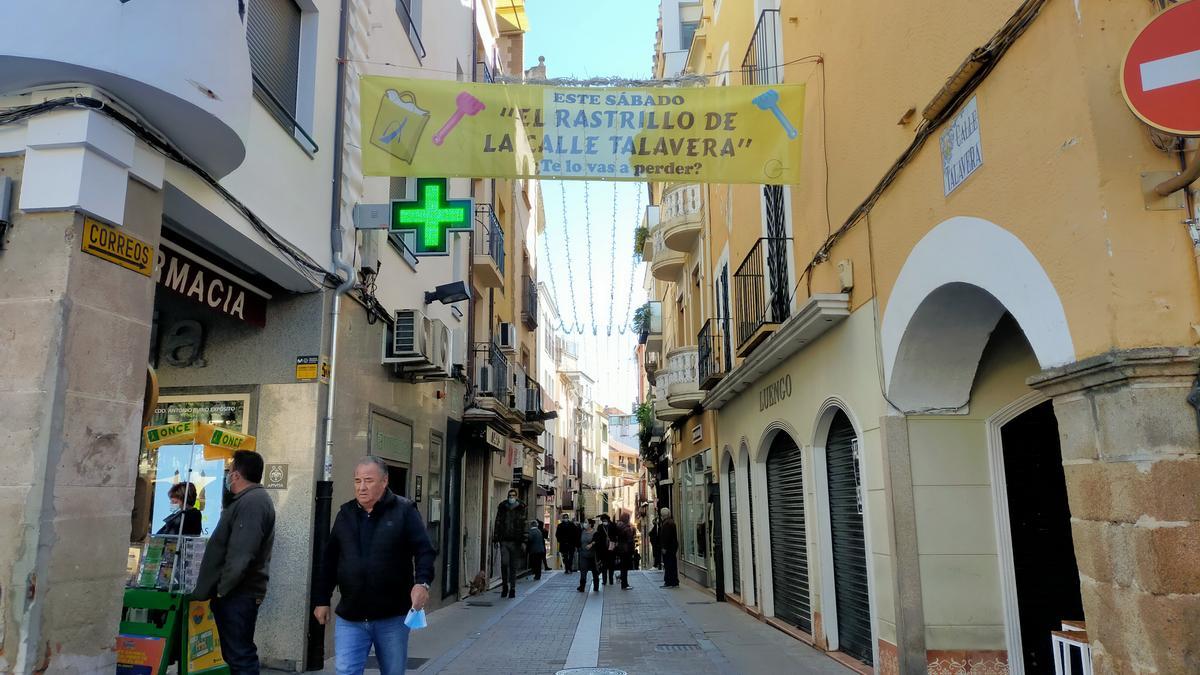 La calle Talavera, con el cartel informativo de su rastrillo a favor de Feafes Plasencia, este jueves.