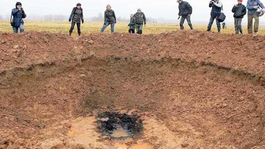 Científicos y periodistas observan el cráter que causó el supuesto meteorito que cayó en Letonia