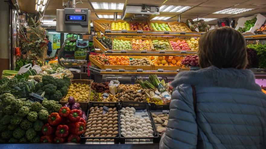 Una mujer observa frutas y verduras en un puesto del Mercado Central de Alicante.