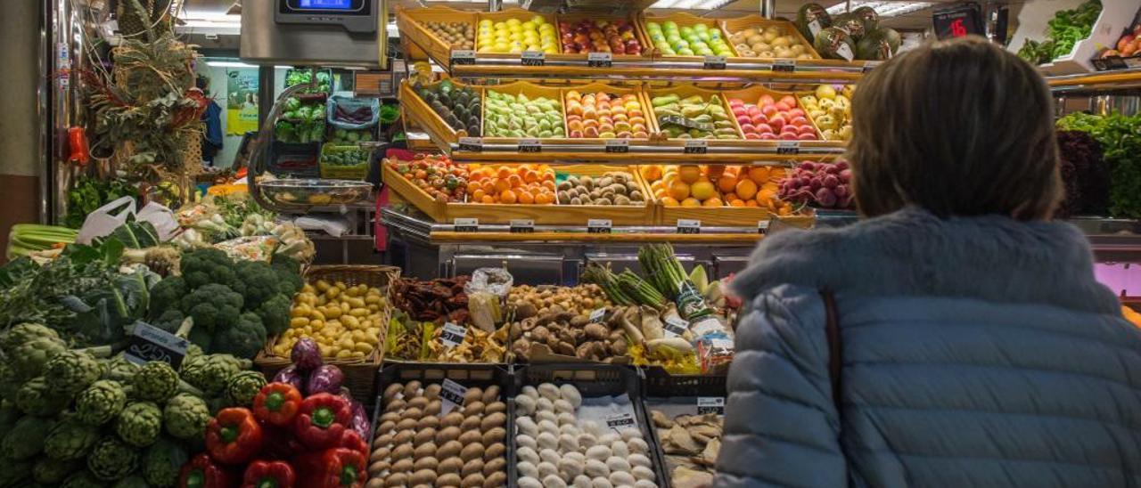 Una mujer observa frutas y verduras en un puesto del Mercado Central de Alicante.