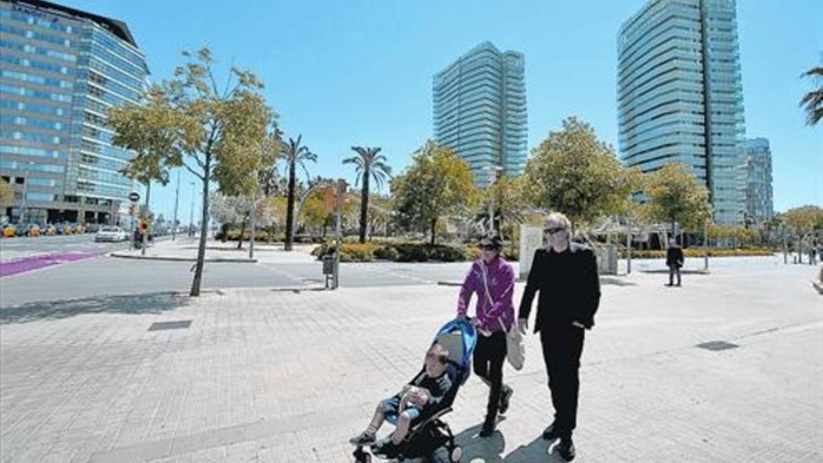 Una familia pasea por el barrio, con las torres que integran el complejo de la Illa del Mar, al fondo, ayer.