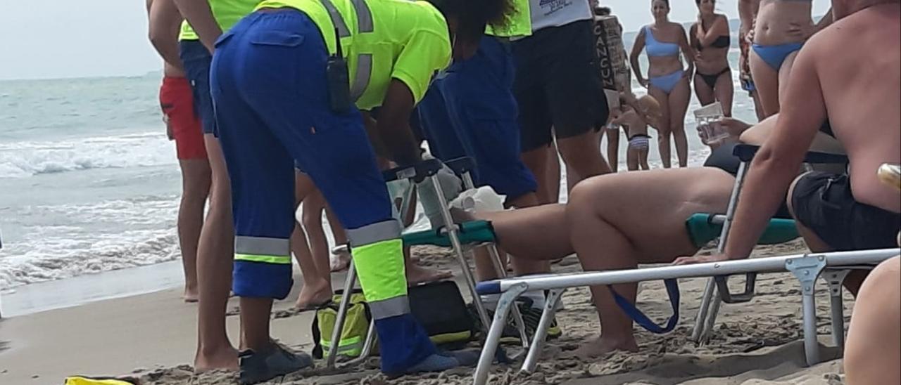 Momento en que la mujer herida en un pie es auxiliada en la playa de El Pinet
