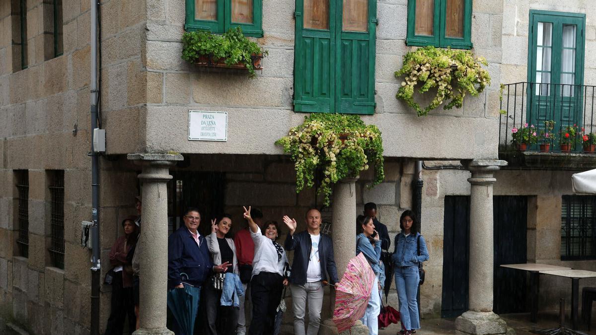 Turistas se refugian de la lluvia en un soportal de la plaza de A Leña.