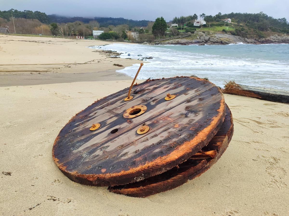 Un carrete de enrollar cable arrastrado por el mar a la playa de Area de Bon.