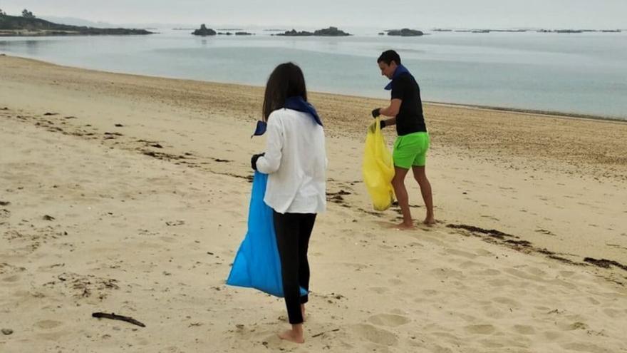 Dúas persoas voluntarias recollendo lixo na praia da Corna /c. pobra