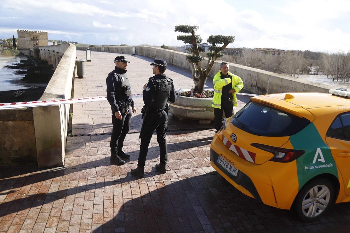 Policía Local en uno de los accesos al Puente Romano, cortado al tránsito de personas por la crecida del Guadalquivir a su paso por Córdoba