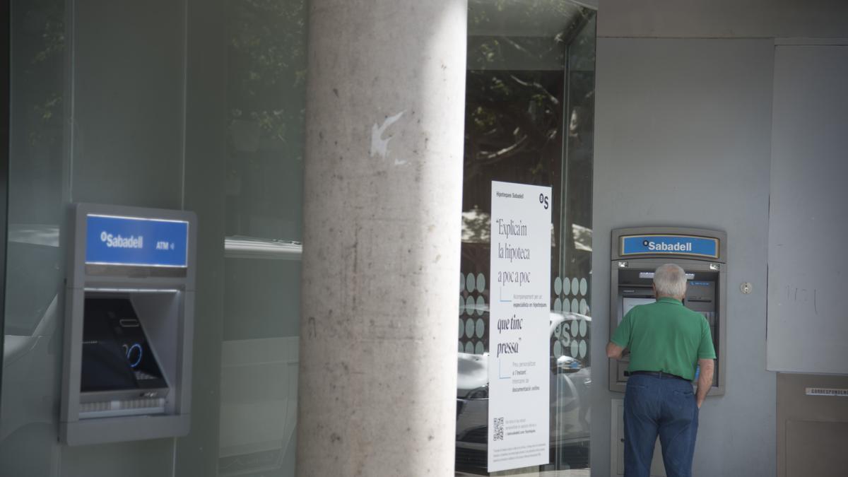 Un usuari retirant diners d'un caixer del Banc Sabadell a Manresa