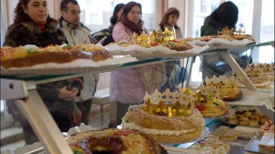 Varias personas, en una pastelería de la ciudad, esperan delante de un expositor repleto de roscones de Reyes