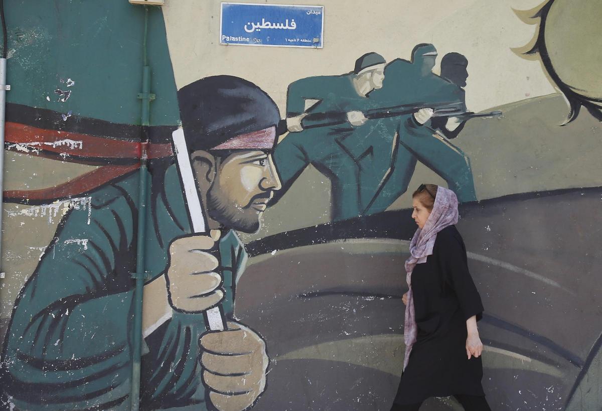 Teherán, Irán 14/04/2024.- Una mujer iraní camina junto a una pintura de la Guardia Revolucionaria Iraní (IRGC).