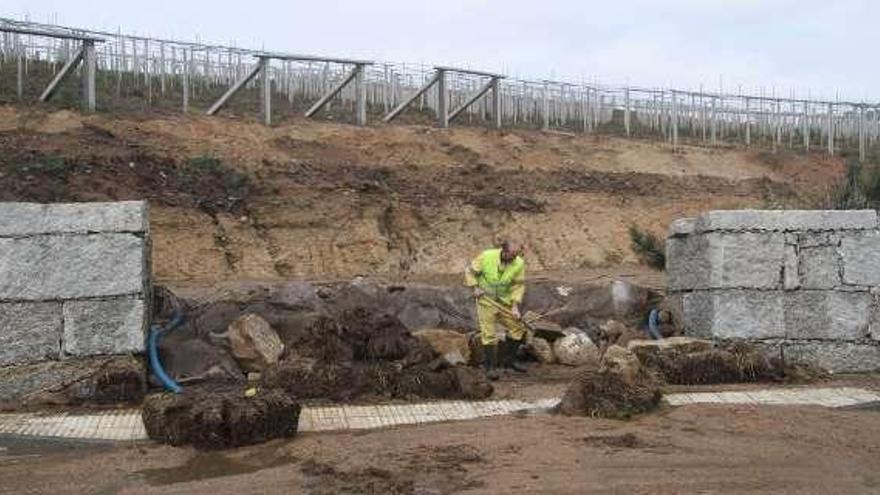 Un operario limpia el cierre, tras la riada del viernes.  // J.L.Oubiña