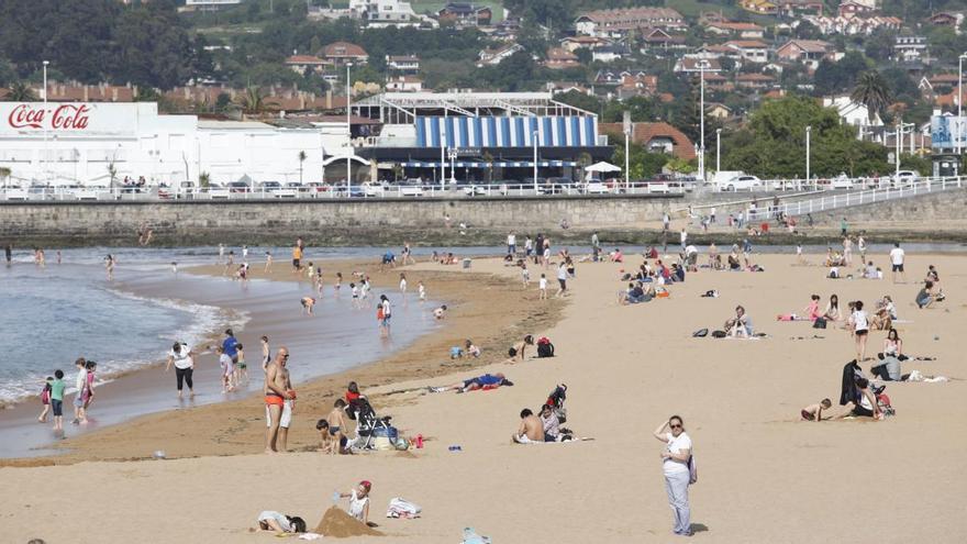 Ciudadanos disfrutando del buen tiempo en el paseo del muro de Gijón.