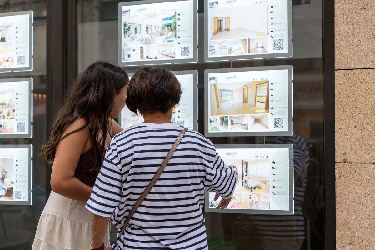 Unos cientes miran los anuncios del escaparate de una inmobiliaria.