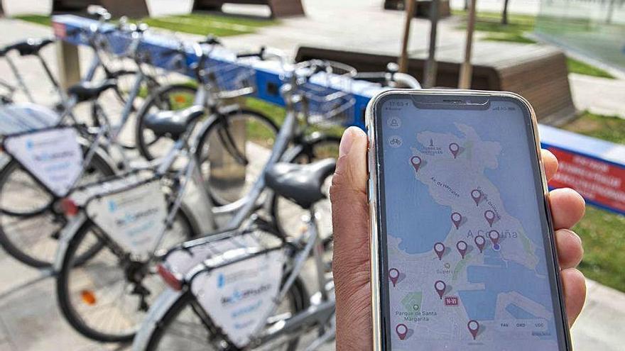 Un teléfono con la aplicación, ante una base de Bicicoruña.