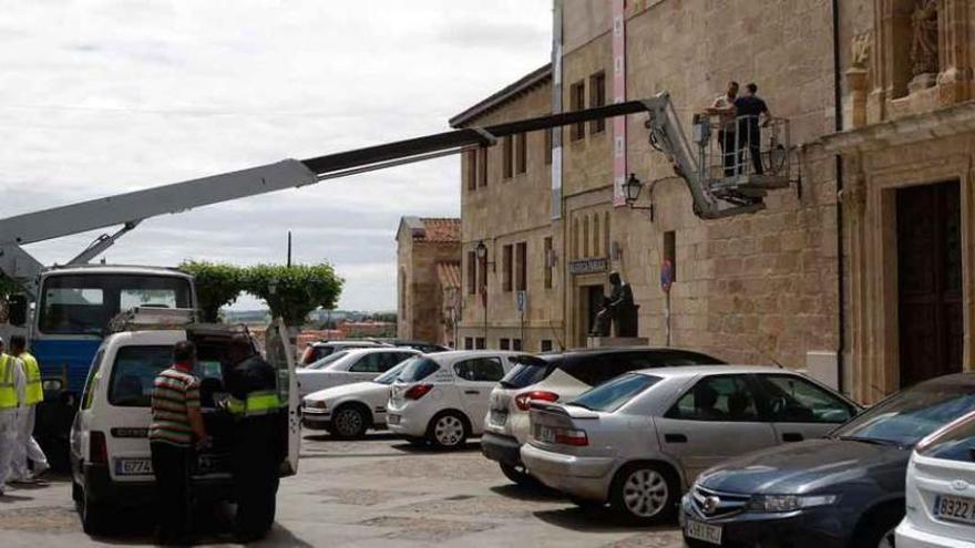 Operarios instalan la iluminación para la Feria de Cerámica y Alfarería Popular en la fachada de la Biblioteca Pública.