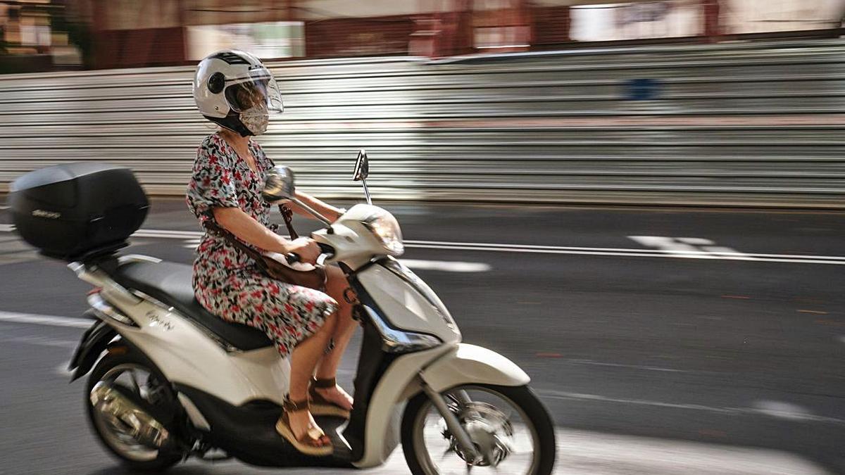 Una mujer con mascarilla en una moto.