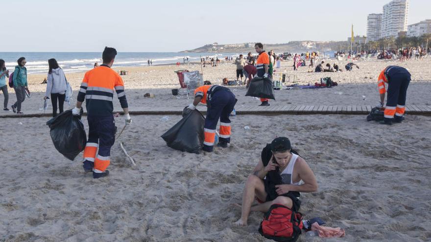 Operarios limpian la playa de San Juan tras el botellón por Santa Faz de 2016