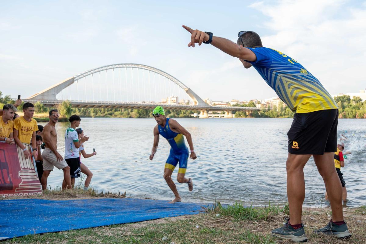 Un triatleta sale del agua durante la competición, con el puente Lusitania al fondo.