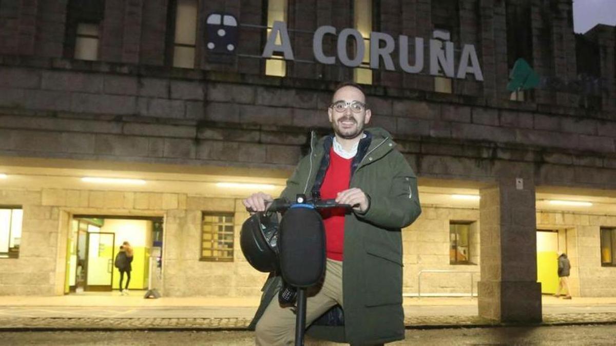 Rubén Suárez, con su patinete eléctrico frente a la estación de tren de A Coruña.