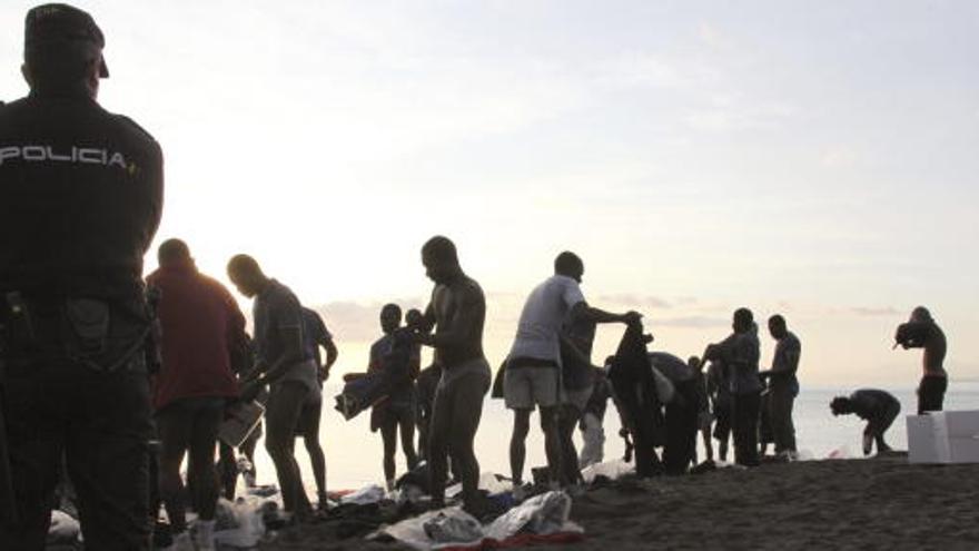 Un policía controla a una serie de inmigrantes ilegales.