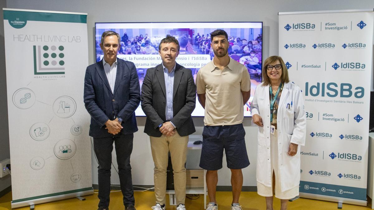 El futbolista Marco Asensio y la gerente de Son Espases, Cristina Granados, en la firma del acuerdo para poner en marcha el programa de atención a los pacientes oncológicos pediátricos.