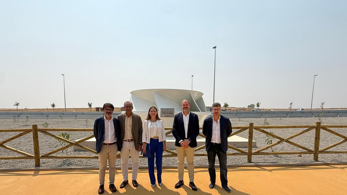 Representantes de la Junta, el Ayuntamiento de Cáceres e Iberdrola posan junto al rodete instalado en una de las rotondas de la Ronda Sur.