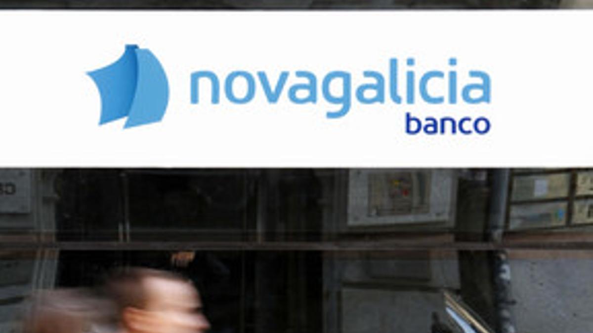 Una pareja con un carro de bebé pasa por delante de una sucursal de Novagalicia, en Vigo.