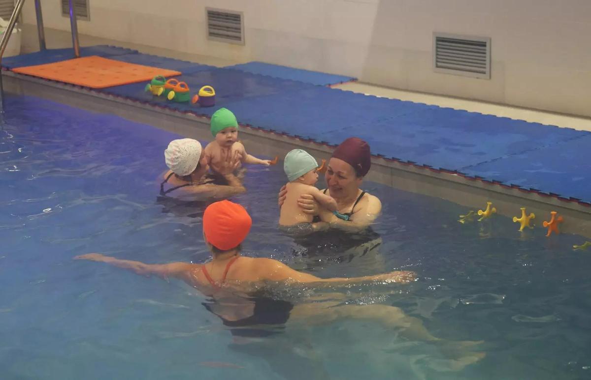 Las familias sostienen en brazos a sus bebés durante toda la sesión en la piscina.
