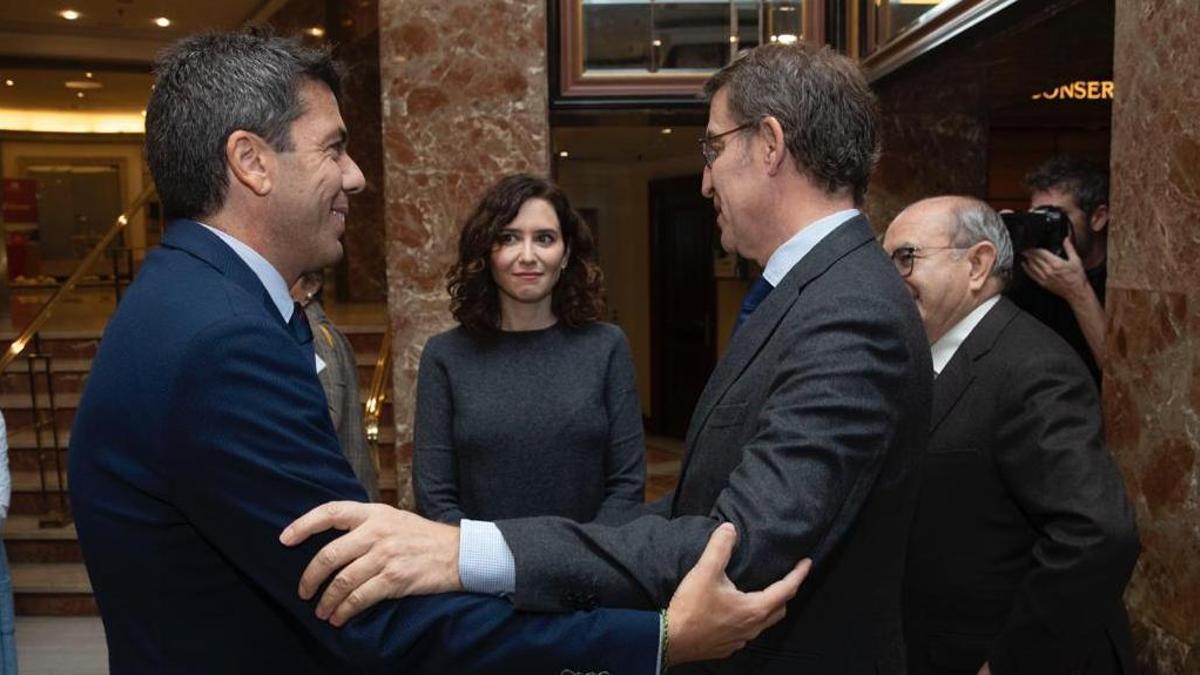 Mazón y Feijóo se saludan en presencia de Ayuso, este lunes en Madrid.