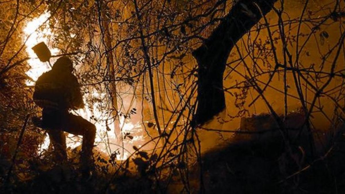 Un agente forestal combate las llamas en el incendio del municipio coruñés de Negreira, el pasado día 11.