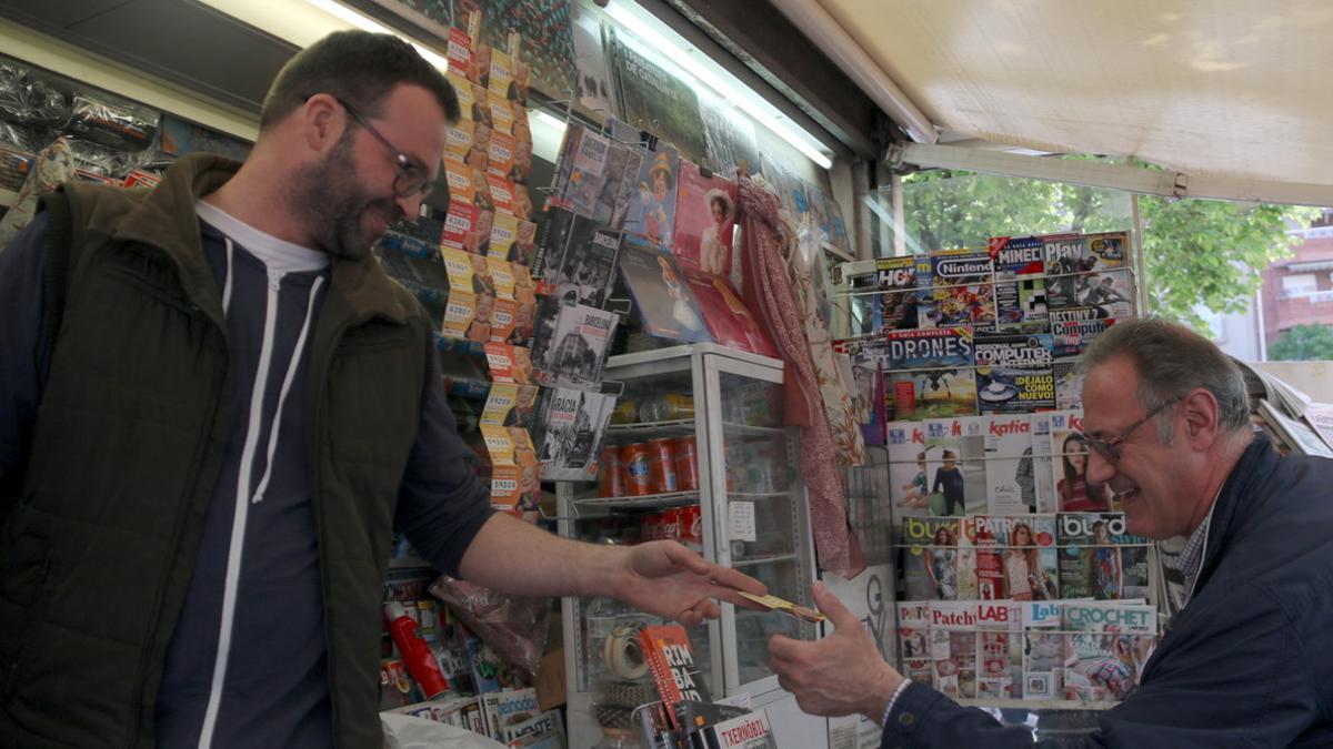 Un hombre compra un billete de la Grossa de Sant Jordi en un quiosco de Barcelona