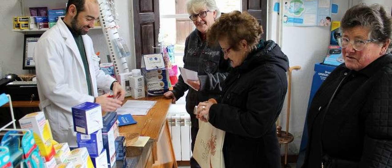 El farmacéutico Víctor Luis González atiende a Carmen Álvarez, Mercedes González y Trinidad Prado.