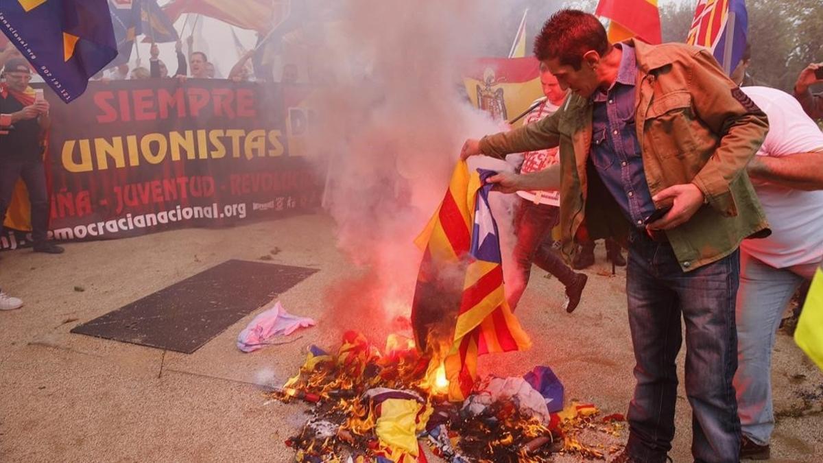 Varios manifestantes de la marcha ultra del 12-O en Barcelona queman una 'estelada'.