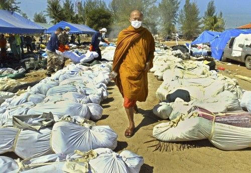 THAI BUDDHIST MONK WALKS PAST WRAPPED BODIES OF TSUNAMI VICTIMS AT KHAO LAK, PHANG NGA PROVINCE