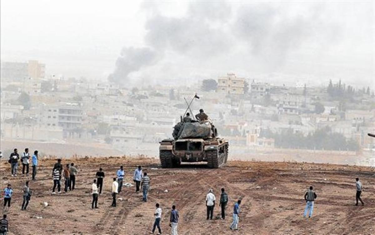 Kurds de Turquia observen prop d’un tanc les columnes de fum que surten de la ciutat siriana de Kobani. Kurds de Turquia observen prop d’un tanc les columnes de fum que surten de la ciutat siriana de Kobani.